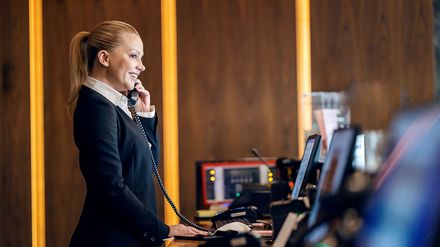 Rezeptionistin in einem Hotel telefoniert an der Rezeption und organisiert den laufenden Betrieb