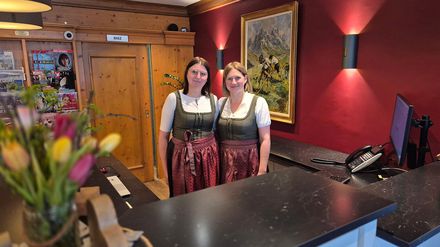 Melanie Panholzer und Melanie Kaden-Kasischke stehen nebeneinander im Hotel Zugspitze und bilden gemeinsam die Leitung der Rezeption.