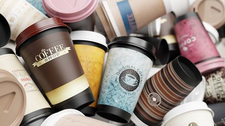 Haufen aus gebrauchten Einweg-Kaffeebechern mit Deckeln als Symbol für Verpackungsmüll im To-go-Bereich