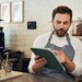 Mitarbeiter in einem Café besprechen am Tablet digitale Bestellungen, Bewertungen und Abläufe