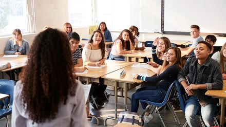 Lehrerin steht vor einer Schulklasse und unterrichtet Schüler im Klassenraum