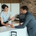 Hotelmitarbeiterin zeigt einem Gast an der Rezeption digitale Informationen auf einem Tablet
