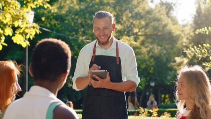 Kellner nimmt im Außenbereich eines Restaurants die Bestellung von Gästen auf