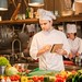 Koch bereitet in einer Restaurantküche frische Zutaten für ein Gericht zu.