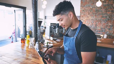 Ein Restaurantmitarbeiter bedient in einem Café ein Tablet an der Theke