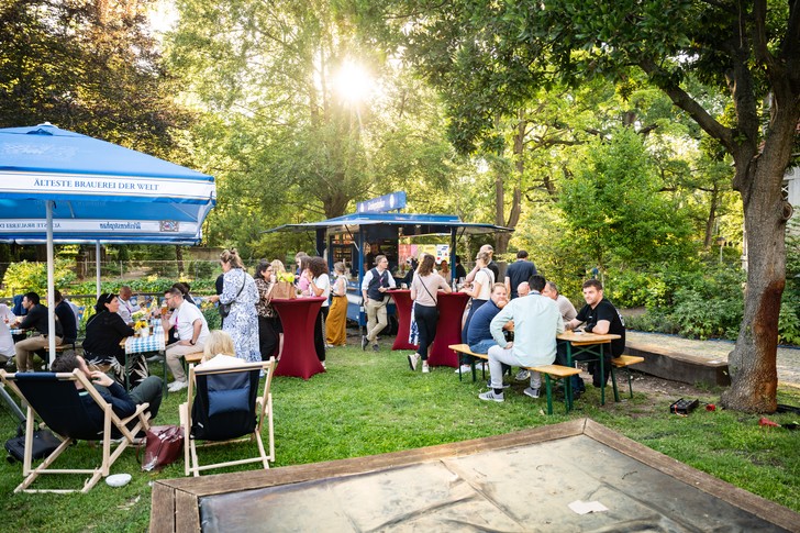 Teilnehmer des UPNXT Hospitality Festivals 2026 tauschen sich auf der Außenfläche der Veranstaltungslocation in Berlin in lockerer Festivalatmosphäre aus.
