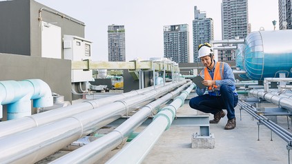 Techniker kontrolliert die Heizungs- und Warmwasseranlage auf dem Dach eines Hotels.