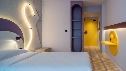 Modernes Hotelzimmer im Radisson in Danzig mit farbigen Designelementen und gelber Eingangstür.