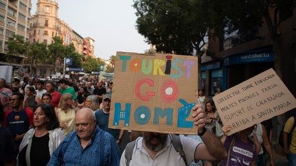 Ein Teilnehmer des Protestzugs in Palma hält ein Schild mit der Aufschrift "Tourists go home" während einer Demonstration gegen den Tourismus auf Mallorca.
