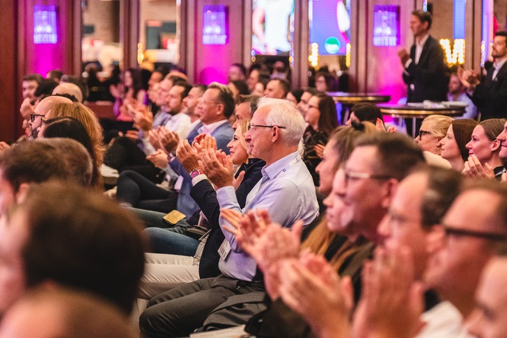 Teilnehmerinnen und Teilnehmer des HSMAday 2025 applaudieren während des Fachprogramms im Veranstaltungssaal.