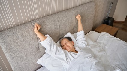 Frau wacht in einem Hotelzimmer auf