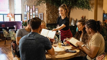 Servicekraft bringt Speisen an den Tisch