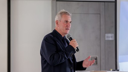 Robert Mangold spricht bei einer Veranstaltung mit einem Mikrofon in der Hand.