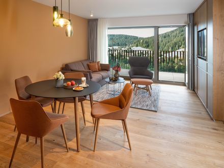 Großzügiger Ess- und Wohnbereich einer neuen Superior-Suite mit rundem Tisch, Sitzgruppe, Balkon und Blick ins Tonbachtal