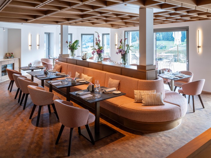Neu gestaltetes Restaurant Silberberg mit geschwungener Sitzbank, gedeckten Tischen, Holzdecke und Zugang zur Terrasse