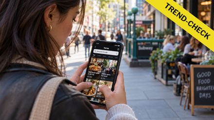 junge Frau blickt ind er City auf ihr Handy bei TikTok