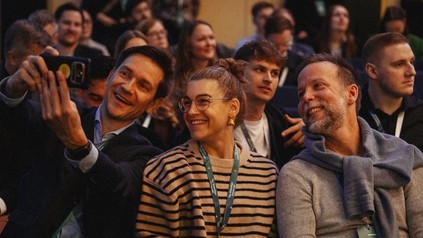 Drei Teilnehmer des GreenSign Future Lab posieren im Publikum lächelnd für ein gemeinsames Selfie.