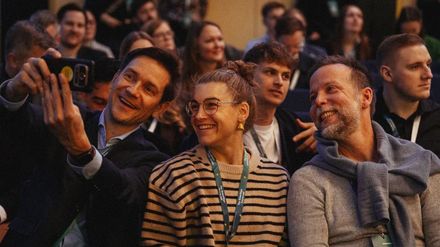 Drei Teilnehmer des GreenSign Future Lab posieren im Publikum lächelnd für ein gemeinsames Selfie.