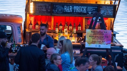 Mehrere Menschen tummeln sich vor einem Stand namens Bar Truck