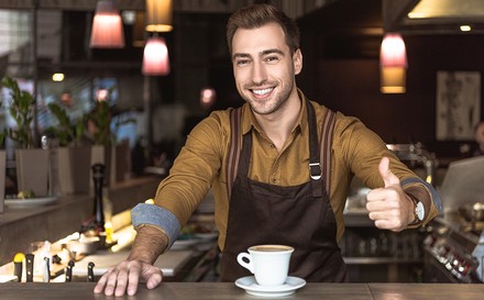 Kellner am Tresen zeigt Daumen hoch