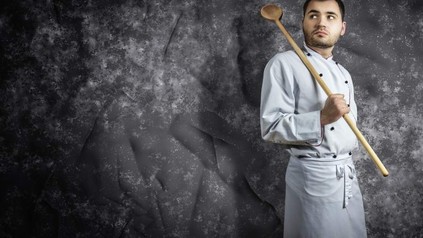 Koch mit riesigem Kochlöffel über Schulter