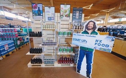 Ein Regal in einem Metromarkt mit einem Aufsteller auf dem Start Ups NX Food steht