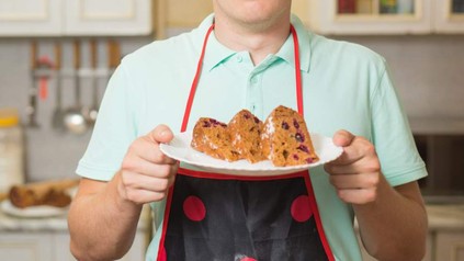 Koch mit Kuchen in der Hand und Mehl im Gesicht