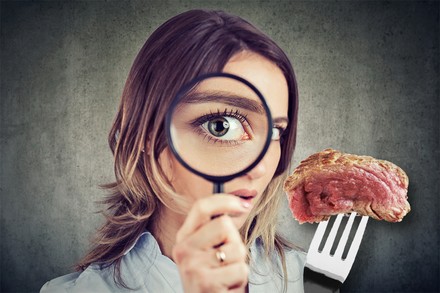 Eine Frau inspiziert ganz genau ein Stück Fleisch