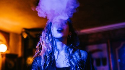 Junge Frau raucht in einem Nachtlokal