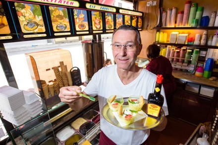 Uwe Hoffmann hält ein Tablett mit drei Eisbechern und einer Flasche Maggie Würze