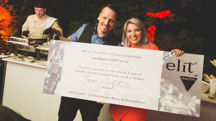 Natascha Rauchwarter und Tom Sipos halten ein Schild hoch, das Tom Sipos als Sieger der elite art of martini-competition auszeichnet
