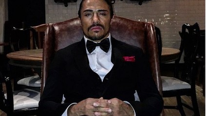 Nusret Gökçe mit Anzug auf Sessel