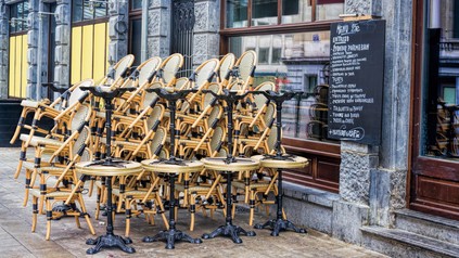 Tische und Stühle gestapelt vor geschlossenem Restaurant