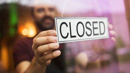 Besitzer hängt Geschlossen-Schild an Restauranttür