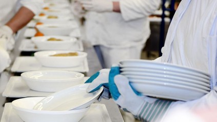 Küchenkräfte bereiten Essen auf Tabletts vor
