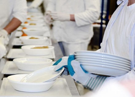 Küchenkräfte bereiten Essen auf Tabletts vor