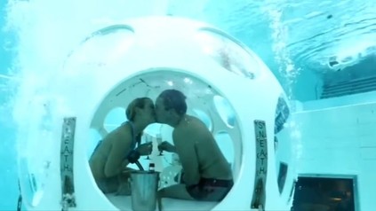 Paar trinkt Sekt unter Wasser in Kugel