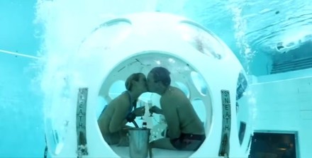 Paar trinkt Sekt unter Wasser in Kugel