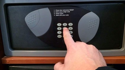 Mann drückt auf Knopf am Hotelsafe