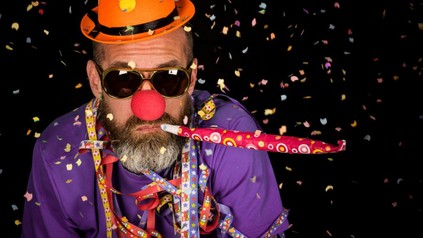 Mann mit Clownsnase und Konfetti in der Luft