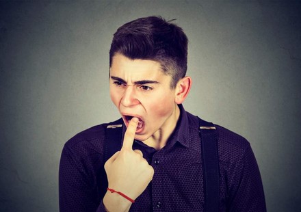 Mann steckt sich Finger in den Hals