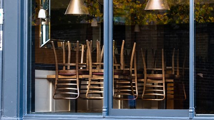 Fenster, durch das man in ein geschlossenes, leeres Restaurant sehen kann, auf den Tischen sind Stühle aufgestellt