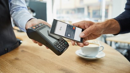 Ein Kunde bezahlt einen Kaffee mit seinem Smartphone über Google Pay