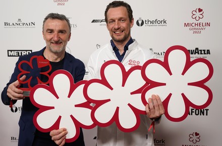 Thomas Schanz und Johannes King halten ihre Michelin-Sterne vor einer Logowand hoch