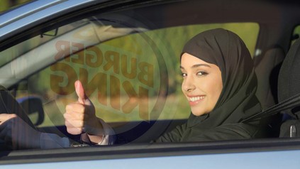 Eine arabische Frau mit Kopftuch hinterm Steuer vor einem Burger King