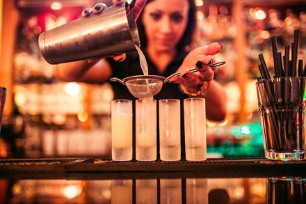 Frau gießt Getränke über Sieb in Shotgläser