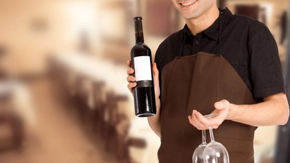 Wirt mit Weinglas und Weinflasche in der Hand