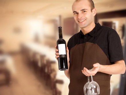 Wirt mit Weinglas und Weinflasche in der Hand