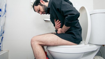 Mann mit Bauchweh auf Toilette