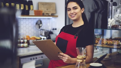 Barista, die mit Schürze hinter der Theke steht